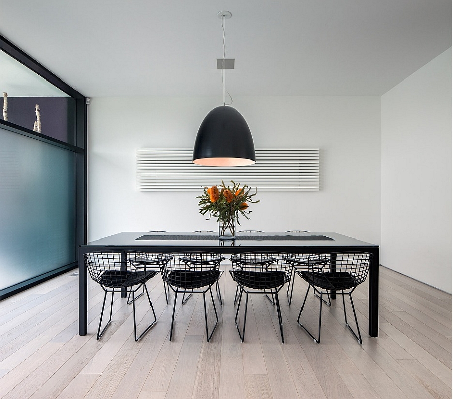 Oversized pendant light iluuminates the sleek, minimal dining space