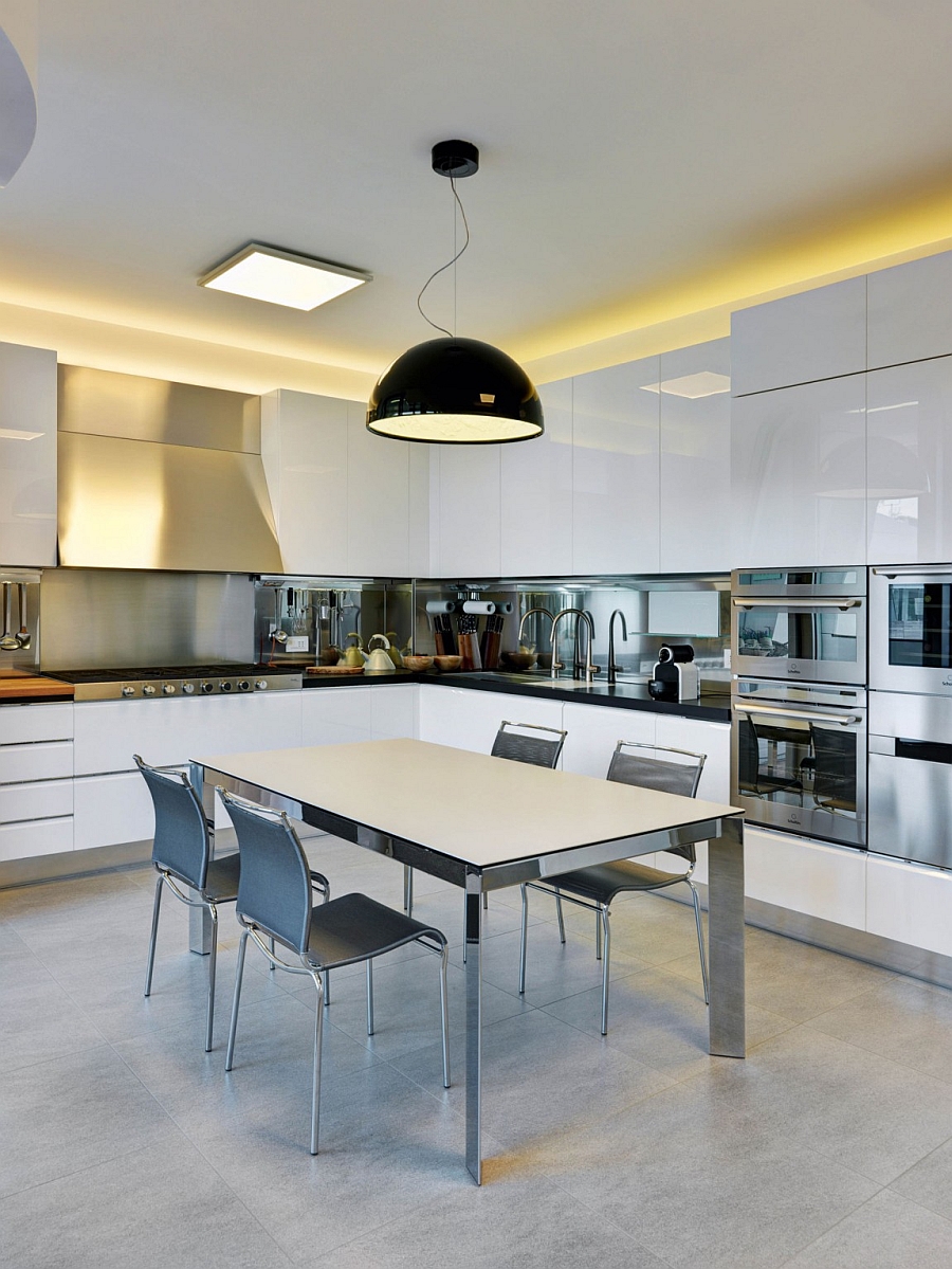 Oversized pendant light in black becomes the focal point of this sleek, white kitchen