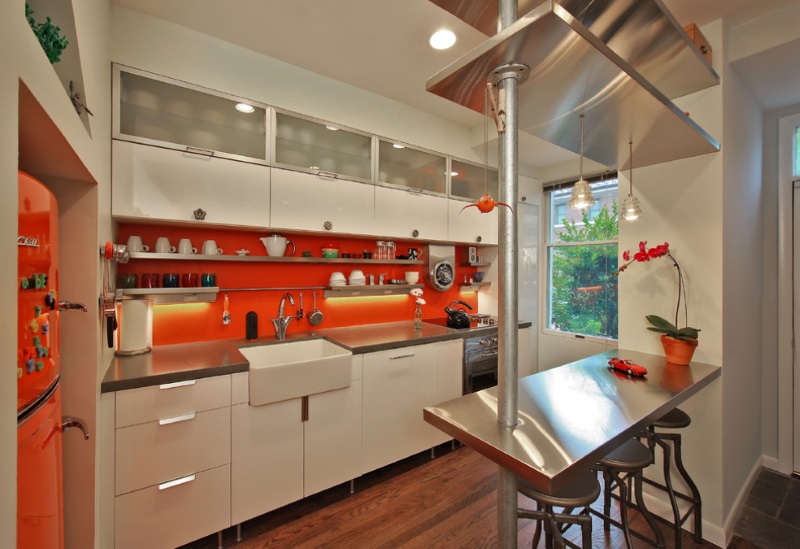 Stainless steel shelving pops against a vibrant orange wall