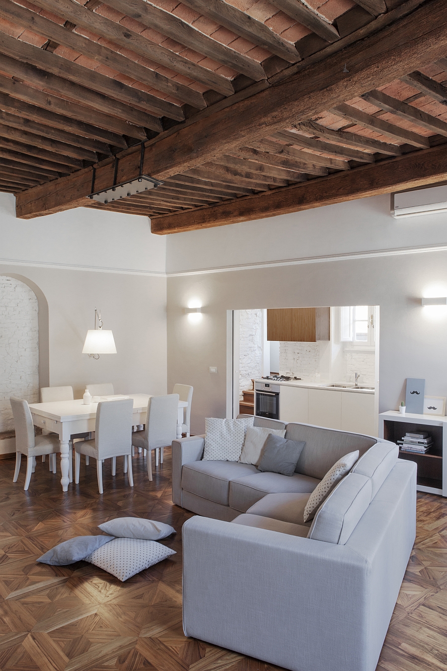 Exposed rafters, teak flooring and brick wall niche add classic charm to the living room