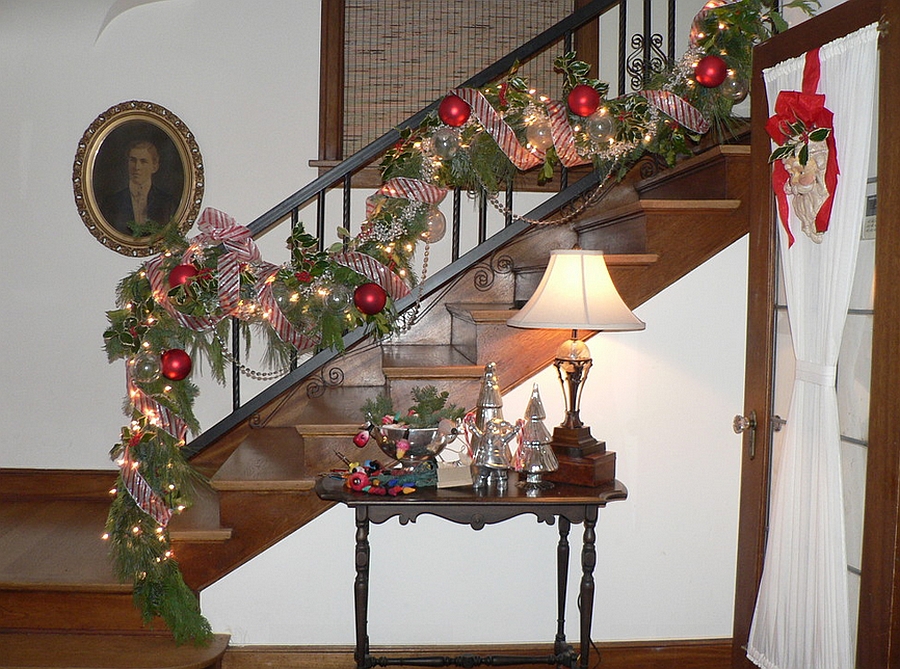 Shiny Christmas ornaments and strings lights used to decorate the staircase [Design: Timothy De Clue Design]