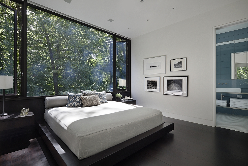 Exquisite bedroom uses large glass windows to offer unabated views of the forest outside