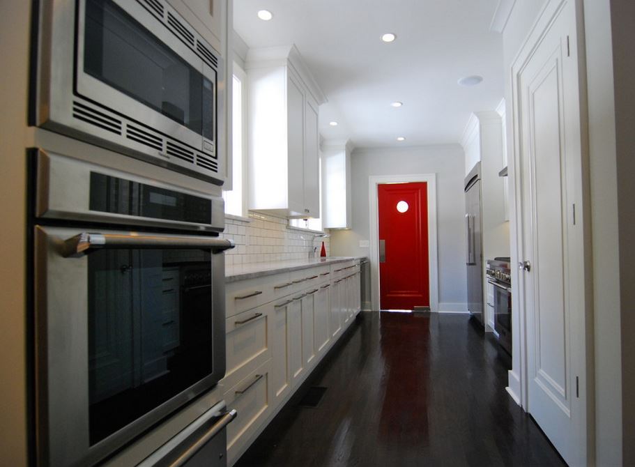 Red door in a white kitchen with dark flooring