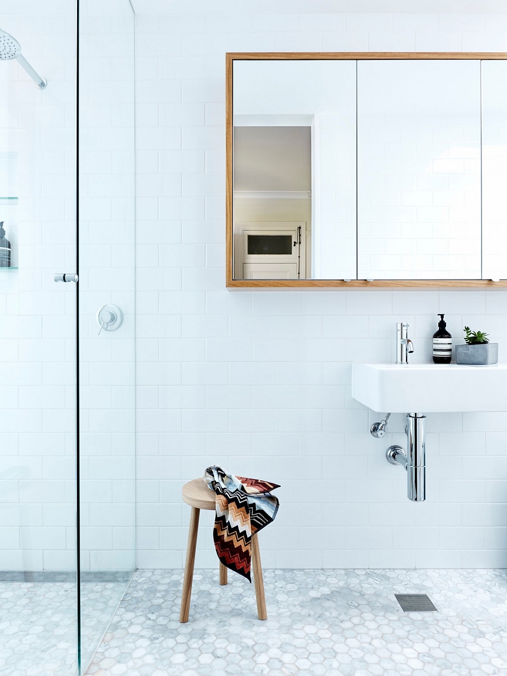 Simple wooden accents bring class and warmth to the contemporary bathroom