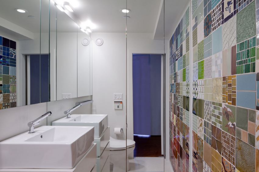 A mirrored wall in a bathroom with colorful tile