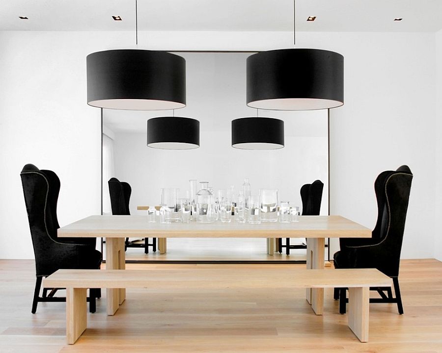 Large black drum pendants add drama to the chic dining room