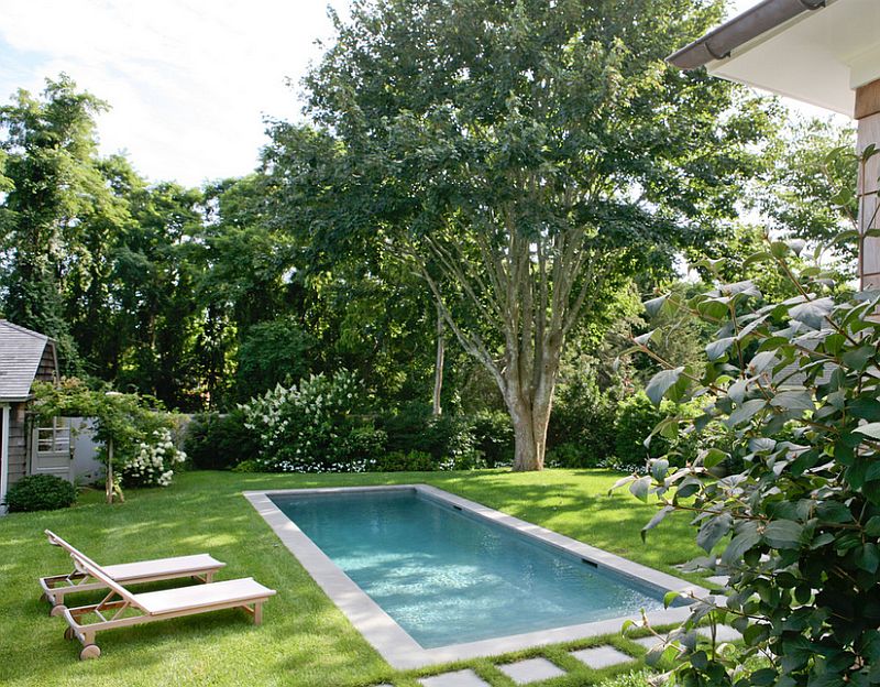 A modest pool with concrete edges and pavers, surrounded by green grass.