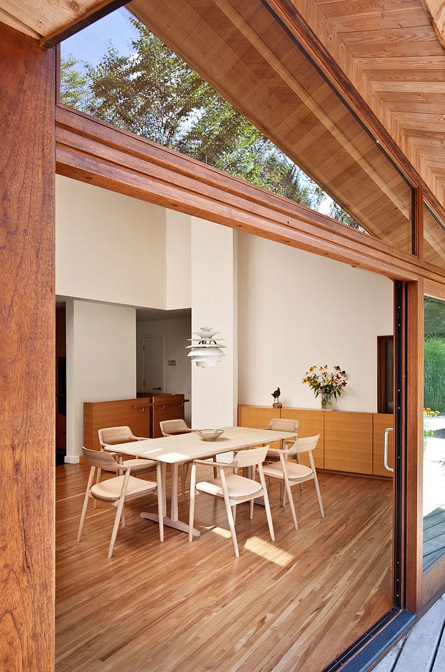 Dining area of the renovated residence with a view of the pond and the landscape outside