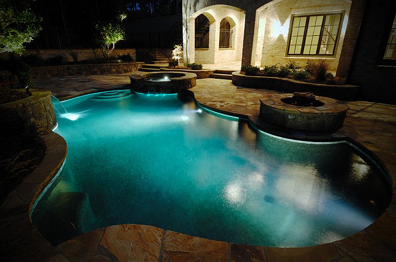 Double water feature around a large pool at night.