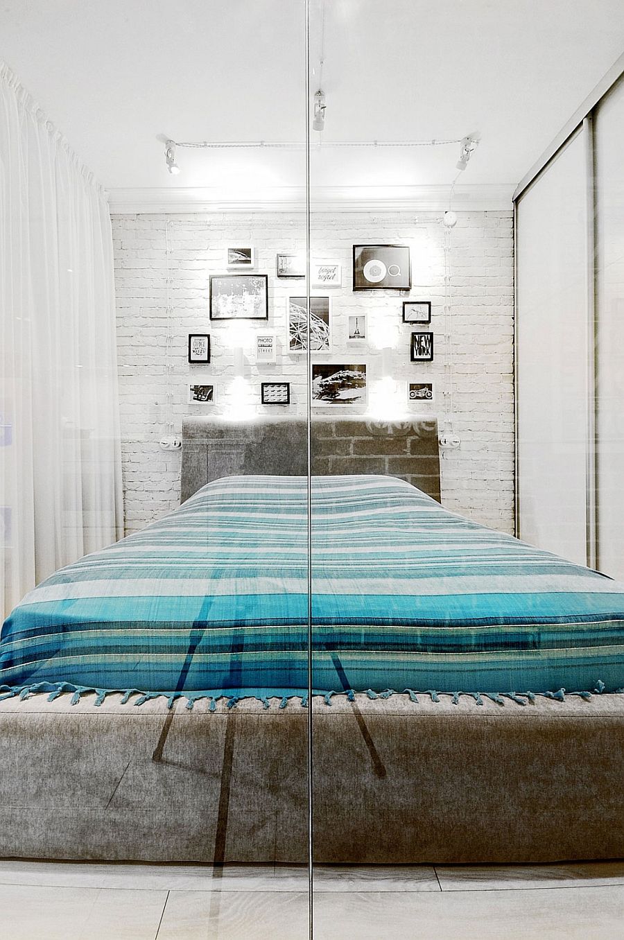 White brick walls offer a unique backdrop in bedroom with glass walls and white drapes