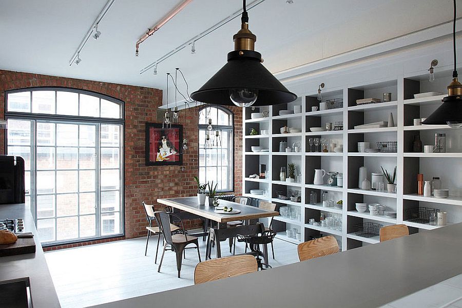 Kitchen and dining room of the industrial London home with a brick wall