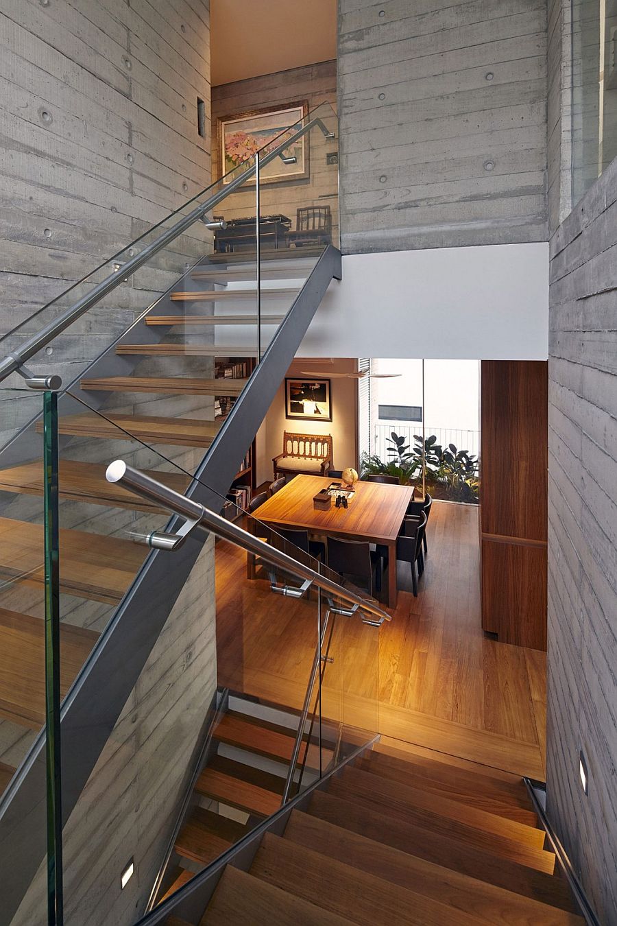 Staircase with wooden steps and glass railing inside the contemporary home