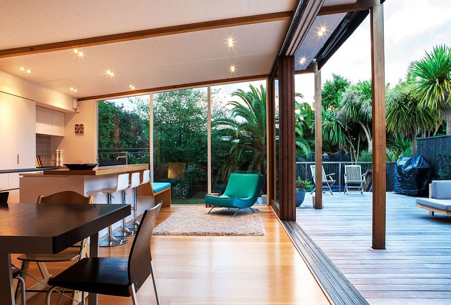 Wall of sliding glass doors connect the kitchen and dining area with thee wooden deck