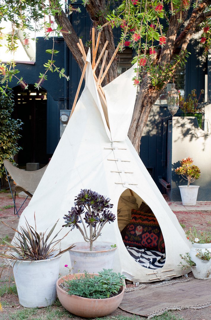 A trio of potted plants in front of a tipi