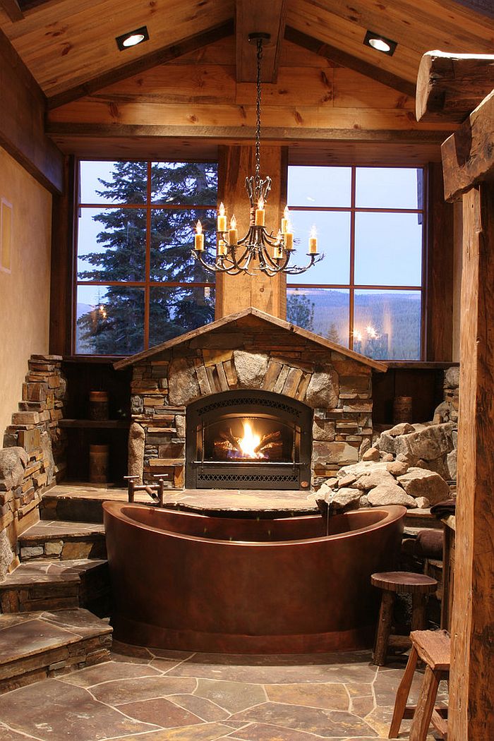 Fabulous cabin-style bathroom with copper bathtub, fireplace and large windows [Design: High Camp Home]