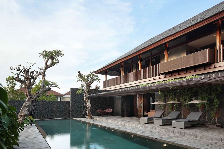 Pool area of the lavish private villa in Bali surrounded by natural greenery and wooden deck