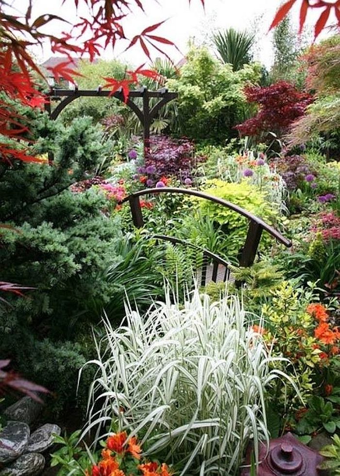 Small garden bridge seems to be engulfed in colorful greenery [Design: Moffet Nursery & Garden Shop]