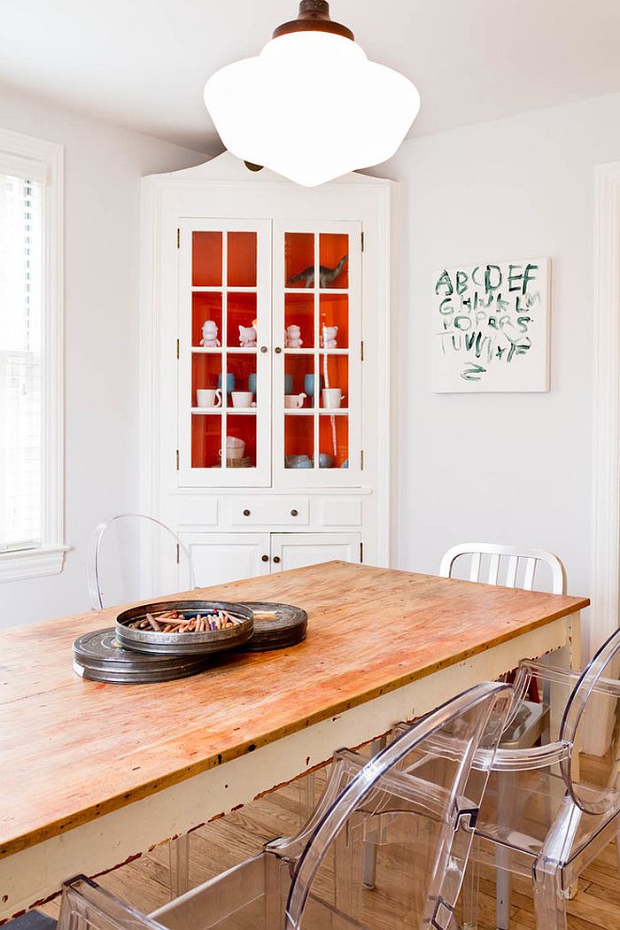 Pops or orange inside the corner cabinet add a touch of playfulness to the dining room