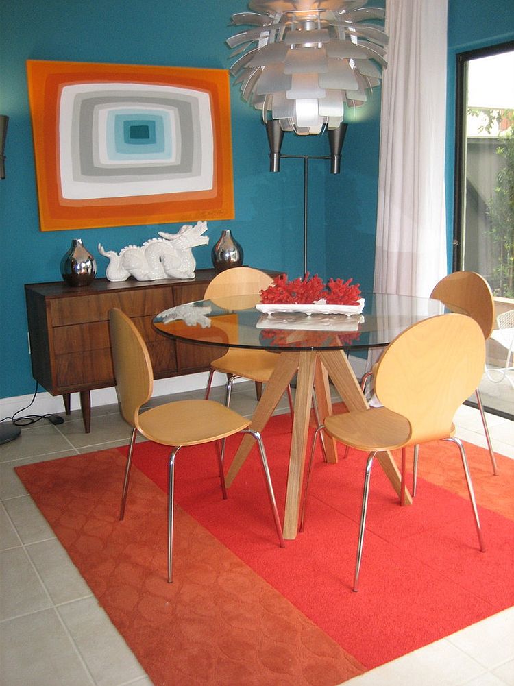 Rug and wall art bring orange into this midcentury dining room