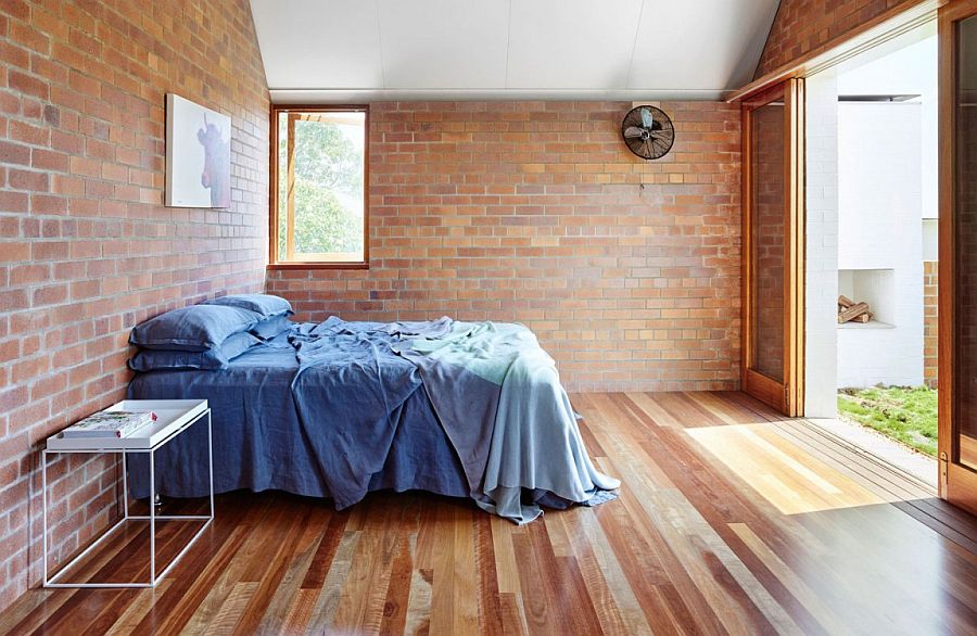 Sliding glass doors connect the brick wall bedroom to the backyard