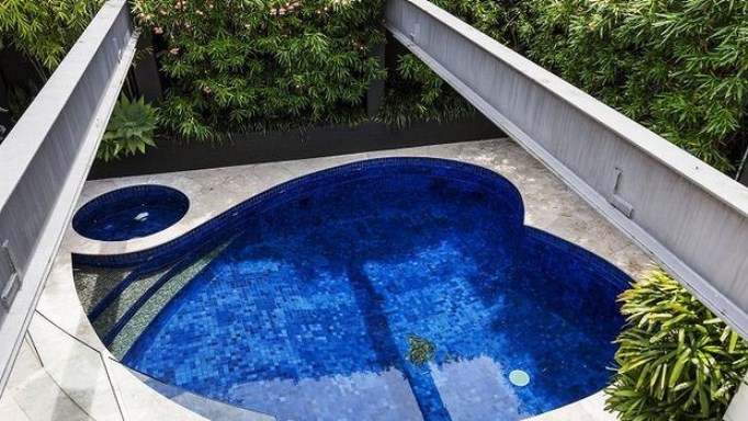 Small heart-shaped pool with a Jacuzzi next to t