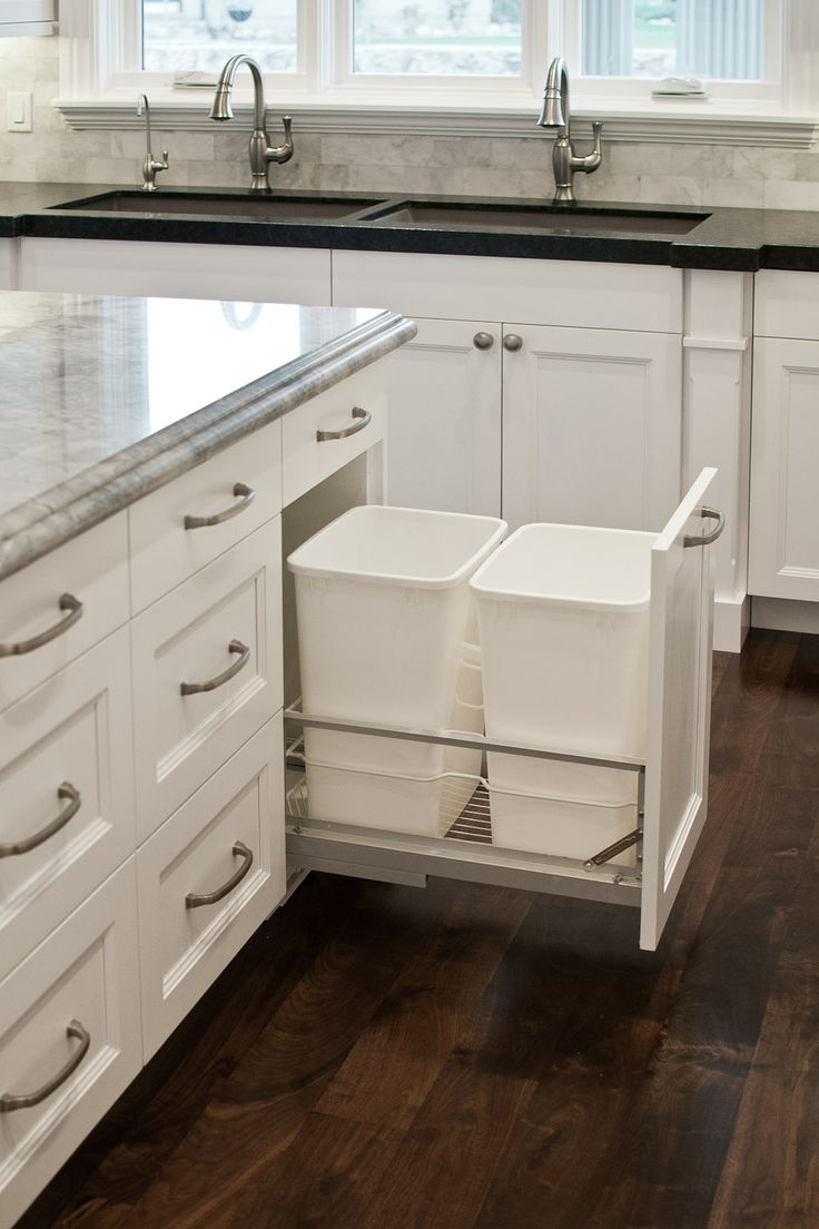 Double garbage cans hidden in white cabinetry