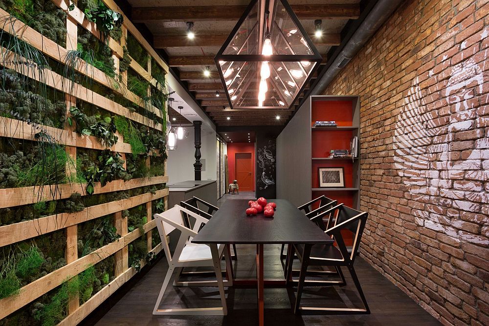 Green wall and brick wall border the intimate dining room with smart lighting