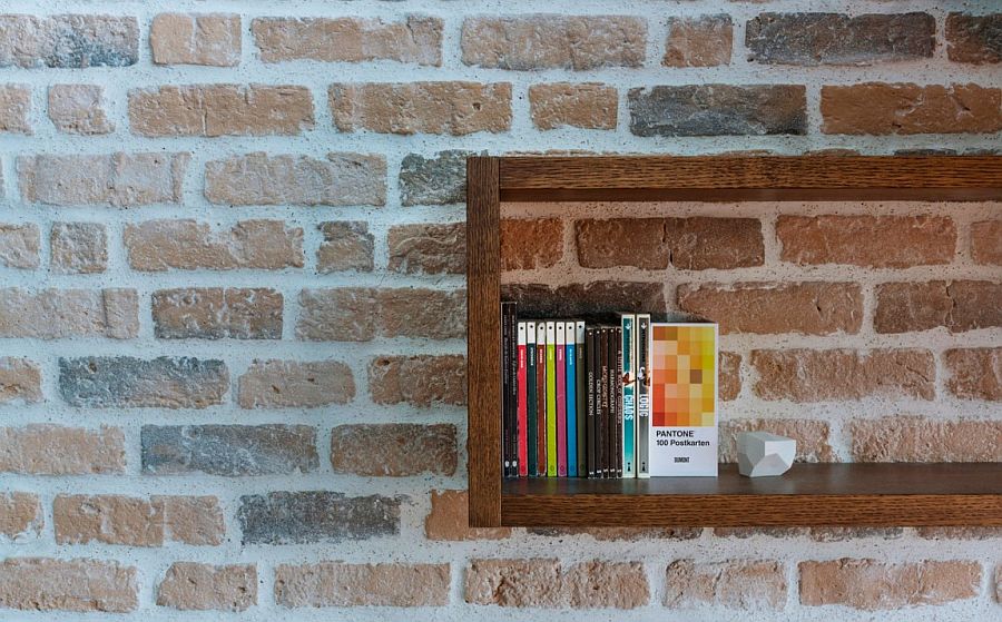 Living room brick wall with floating wooden shelves inside the smart attic apartment