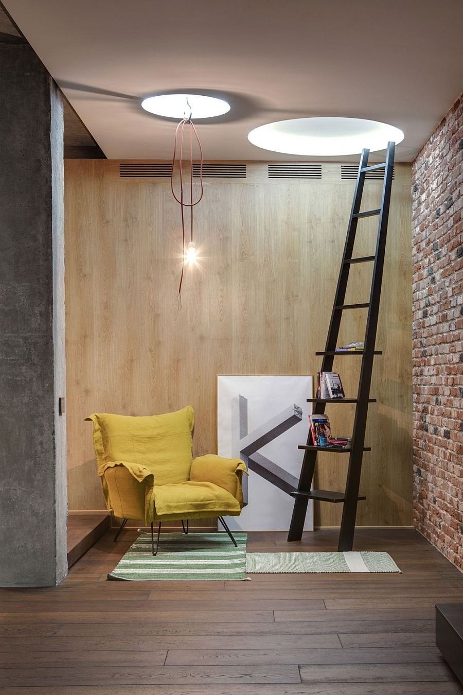 Lovely reading nook with brick wall, bright yellow chair and a stylish ladder used as book rack