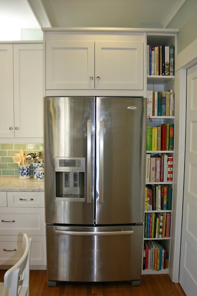 Narrow shelving built into cupboards beside fridge