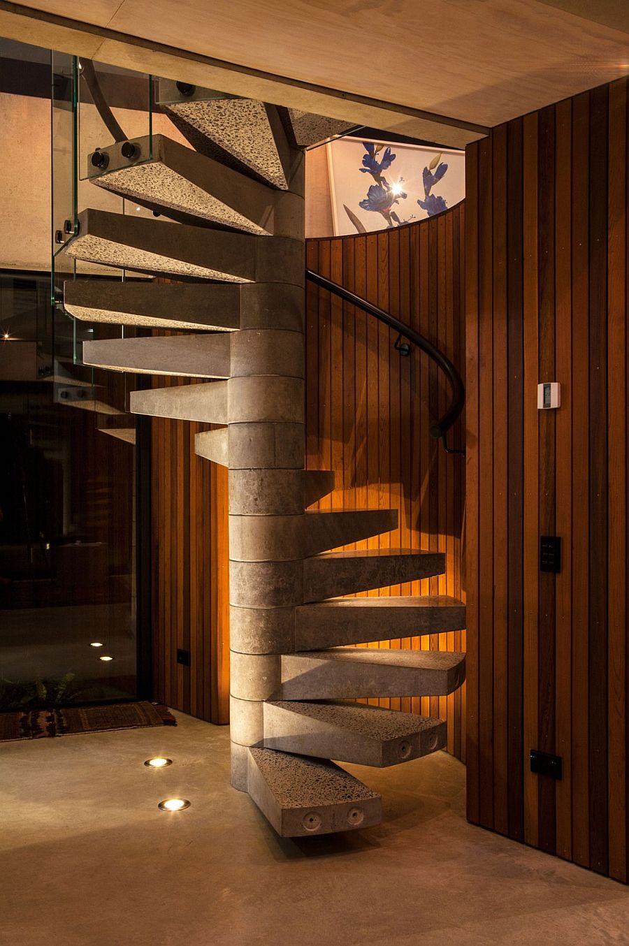 Spiral concrete staircase set against a cedar-clad wall