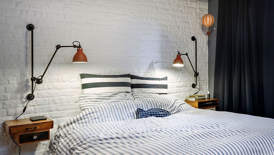 White brick accent wall and vintage bedside lighting inside the small attic bedroom