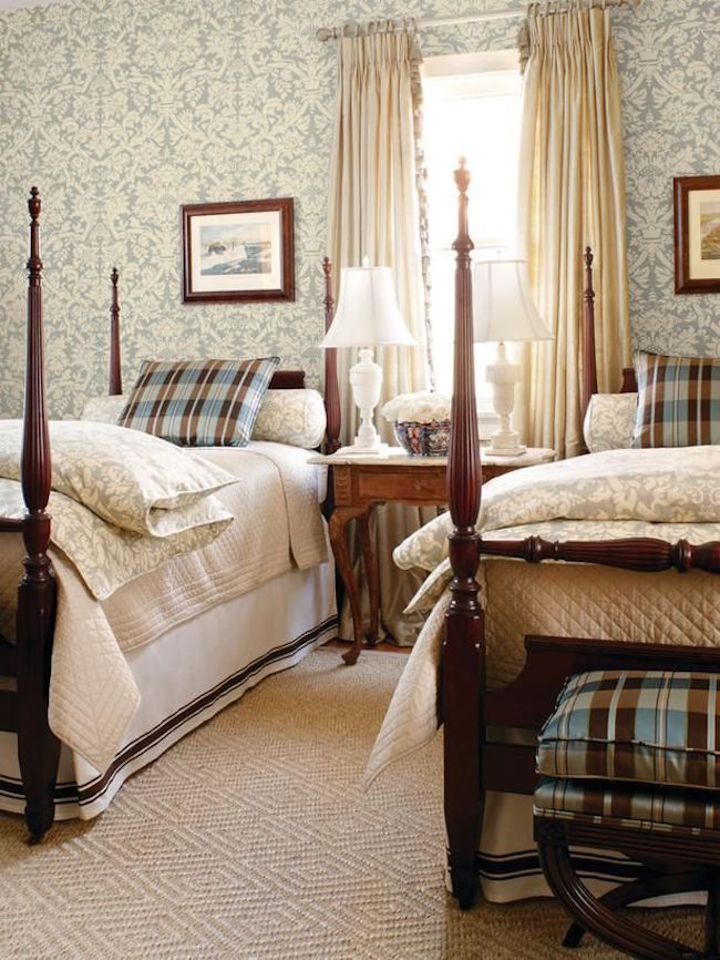 Four post twin beds with elegant bedding and wallpaper