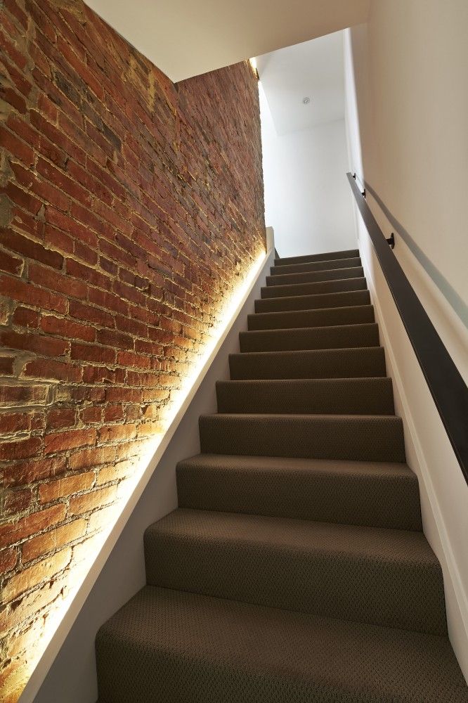 Lighting along the staircase against a brick wall
