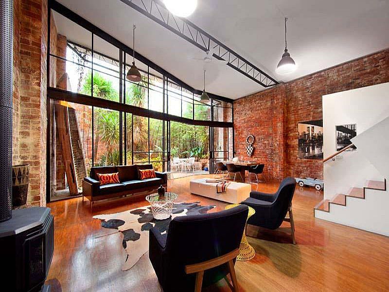 Living room of converted warehouse in Melbourne with brick walls and large glass wall