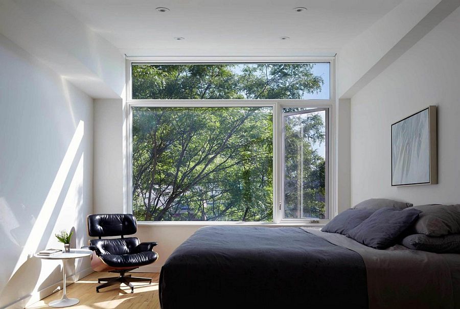 Master bedroom in gray and white with large window and comfy Eames Lounger