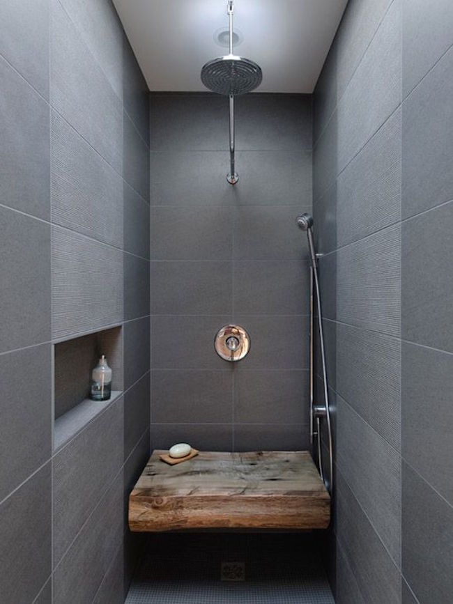 Rustic wood bench in a modern dark tiled bathroom