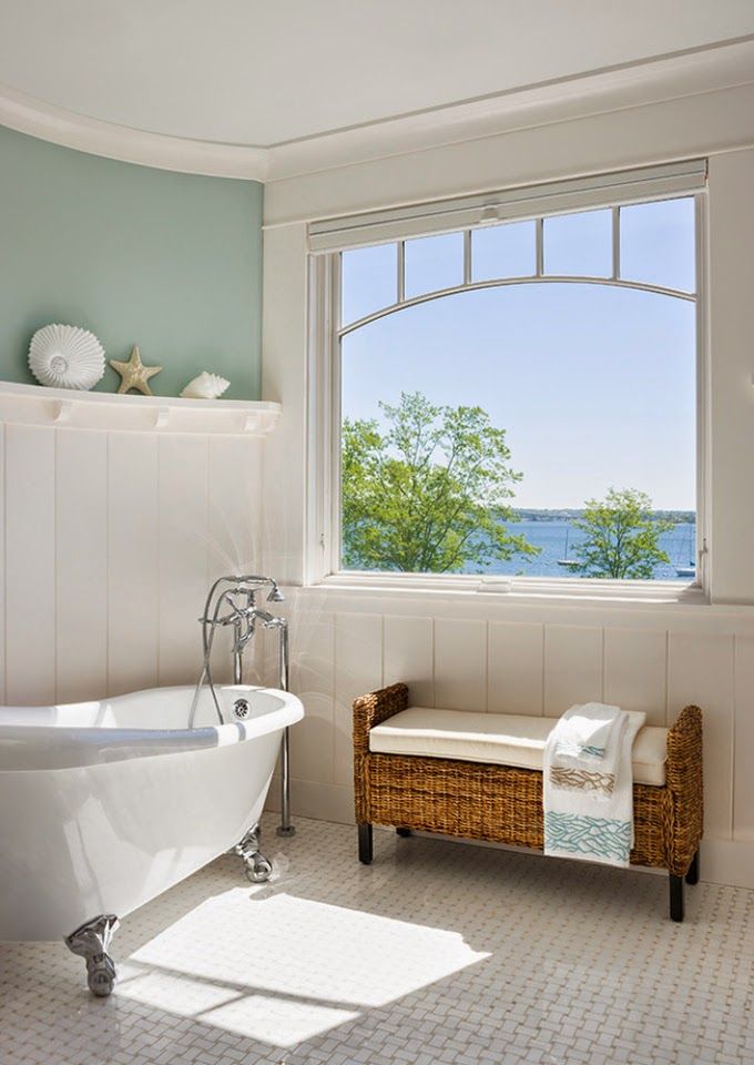 Wicker bench and cushion beneath window in white bathroom