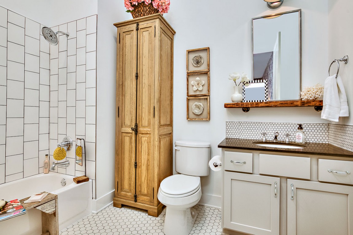 Bathroom in white with penny tiled flooring and wooden cabinet