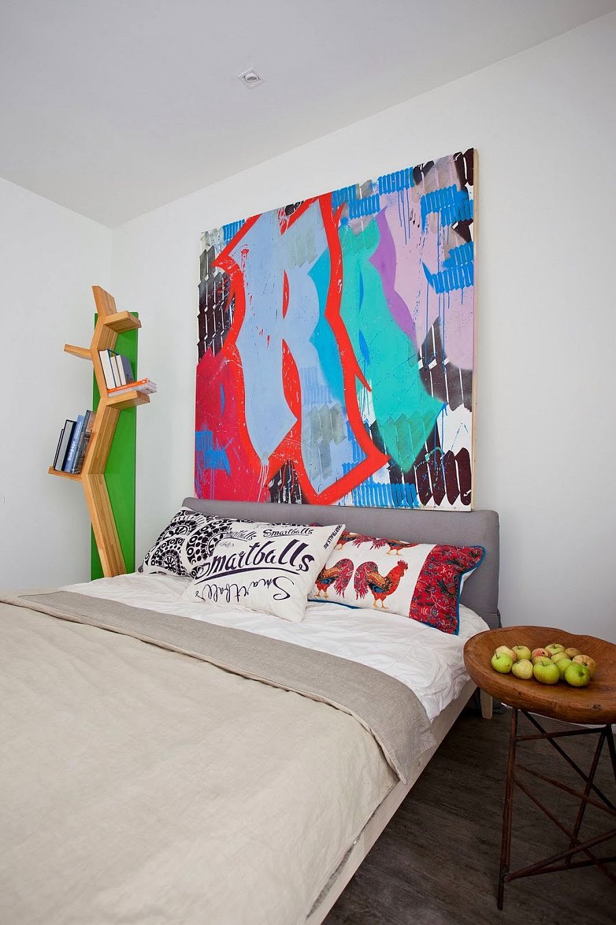 Bookcase, pillows and wall art add color to the white bedroom