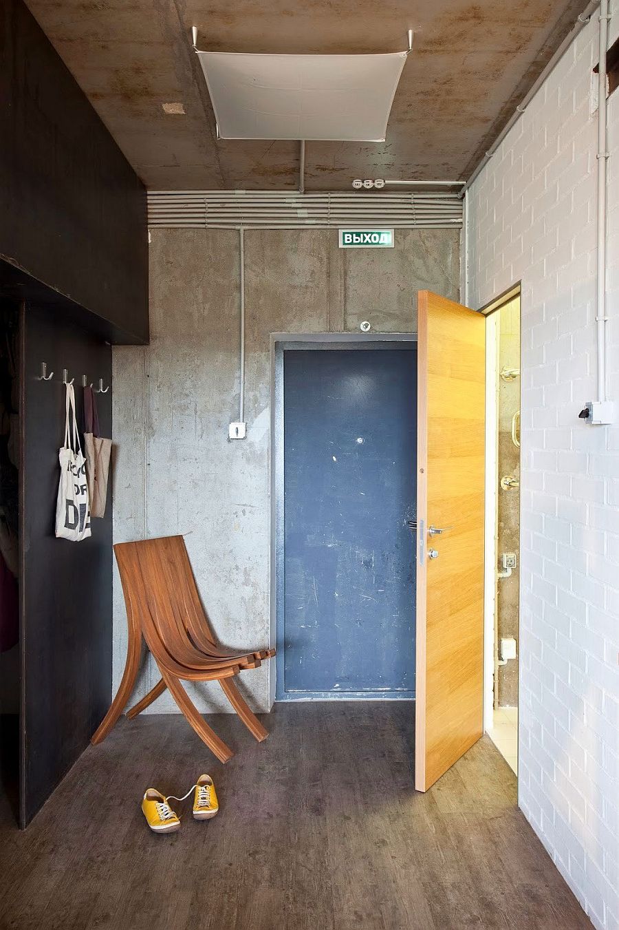 Entrance of the small Russian apartment with exposed concrete and tile walls