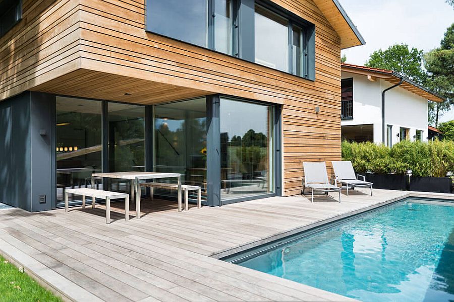 Glass doors connect the living area with the wooden deck and pool outside