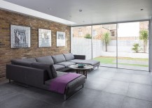 Large-gray-couch-brick-and-glass-walls-create-a-lovely-contemporary-living-room-217x155
