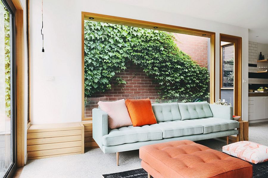 Large wooden bench in the living area with large glass window that looks onto the greenery outside