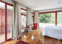 Modern-bedroom-with-white-drapes-glass-doors-with-red-metallic-frames-and-polished-wooden-flooring-217x155