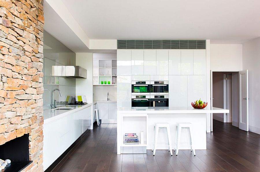 Modern kitchen in white with stone wall fireplace and