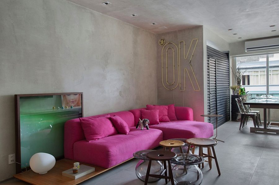 PInk sofa adds color to an otherwise neutral apartment with concrete walls