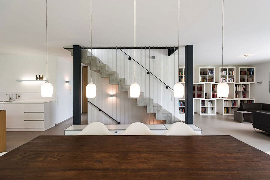 Pendant lights above the dining table complement the design of the staircase in the backdrop