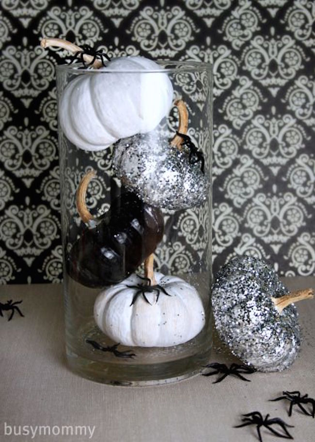 Pumpkins painted black and white in glass cylinder