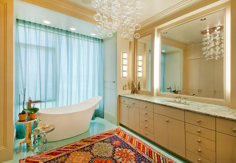 Side tables bring contrasting textures to the glorious bathroom with cascading chandelier